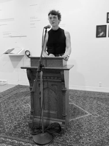 image of CJ Scruton performing at a podium with a microphone